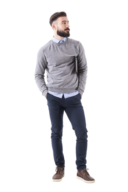 酷放松的现代千禧一代拿着笔记本站着看别处图片下载