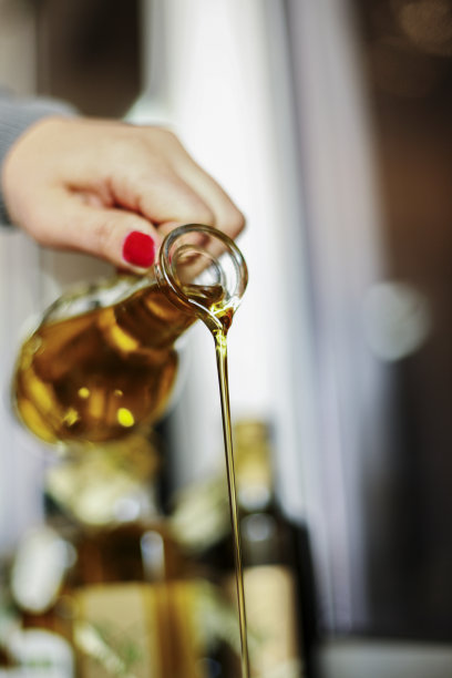 从玻璃瓶中倒橄榄油图片下载