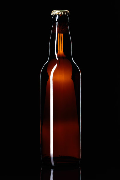 黑色背景下的一瓶啤酒。图片下载