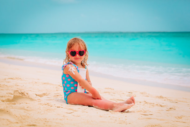 海滩上的防晒——小女孩在肩膀上涂防晒霜图片下载