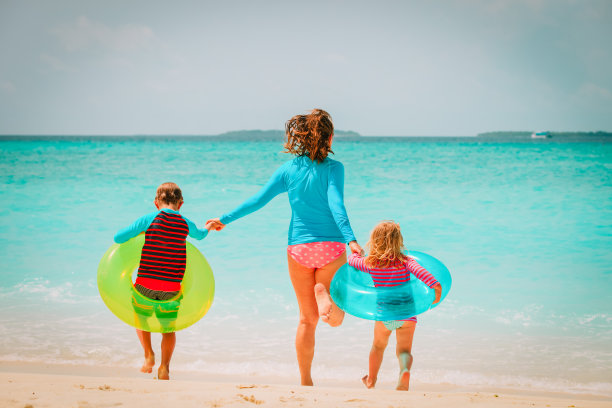 快乐的母亲与儿子和女儿跑在海滩上玩得开心图片下载