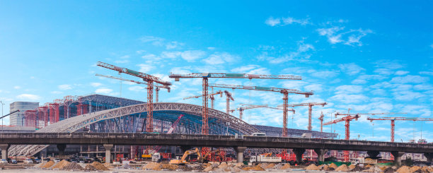以蓝天为背景，一组塔吊运行的建筑施工项目的金属桁架钢结构全景图像图片下载