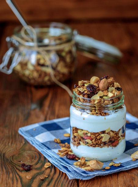 格兰诺拉麦片，酸奶，蜂蜜和巧克力棒放在木桌上。图片下载