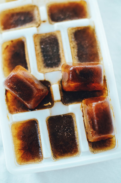 用咖啡制成的冰块放在冰块托盘中，以备提神的咖啡饮料。特写白色背景，柔焦。图片下载