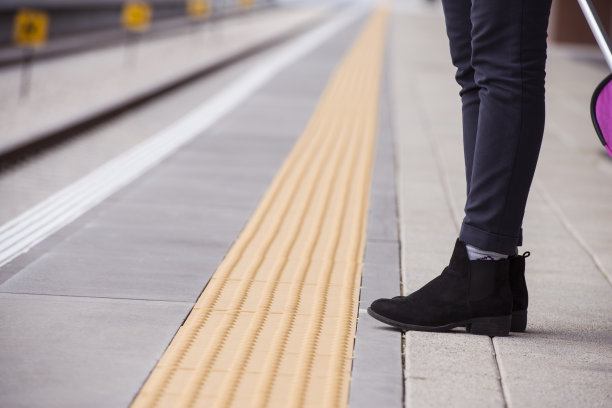 一个女人的腿站在靠近站台上的黄线的特写。图片下载