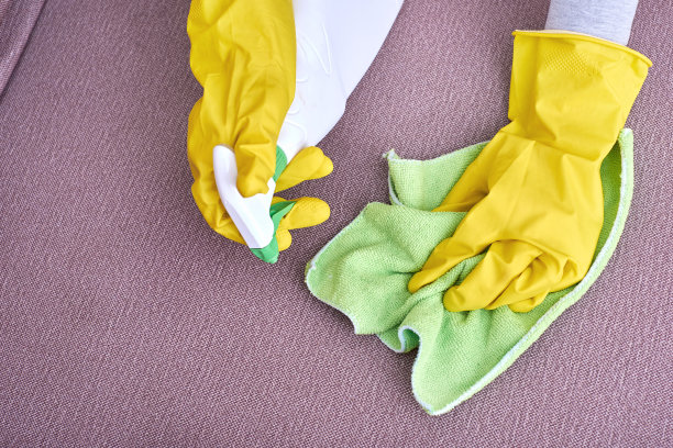 一张戴着黄色手套的手在打扫沙发的照片图片下载