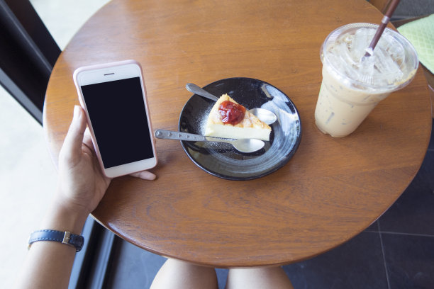 在咖啡店里用智能手机买咖啡和蛋糕的女人。图片下载