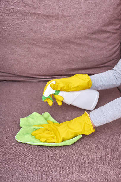 一张戴着黄色手套的手在打扫沙发的照片图片下载