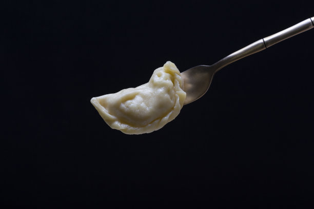 乌克兰和俄罗斯菜- vareniki或饺子与土豆泥或干酪在勺子上在黑色的背景图片下载