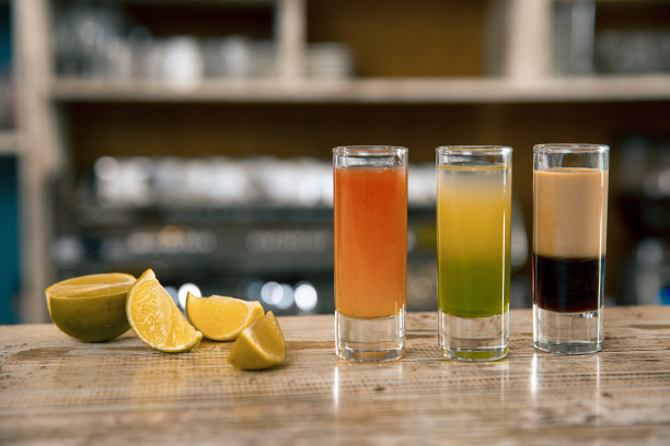 由三种彩色饮料组成的饮料。酒精鸡尾酒与酸橙在酒吧背景。图片下载