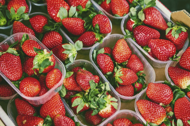 有机天然不完美的水果，有缺陷的塑料容器盒市场上。集市上的天然生态草莓。柔软的潮人复古处理和色调的照片。图片下载