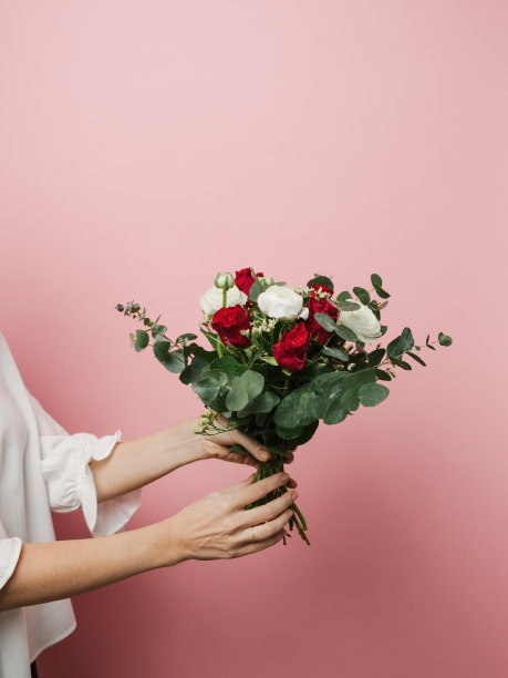 照片中的女人拿着美丽的花束玫瑰粉红色的背景素材图片