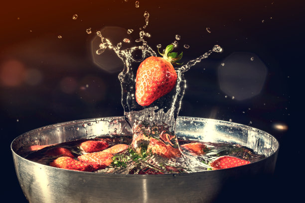 草莓落入水中，在黑色背景上溅起水花。复古复古风格的老照片。图片下载