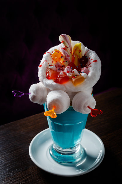 在咖啡馆的桌子上，黑色背景的蓝色奶昔和甜甜圈素材图片