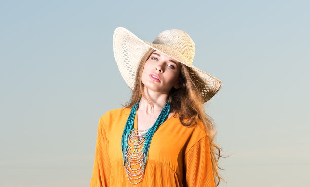 一个戴着帽子的漂亮年轻女人的肖像。红色的裙子和脖子上的装饰图片下载