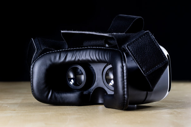 木桌上的虚拟现实眼镜。护目镜和电脑配件。黑色背景图片下载