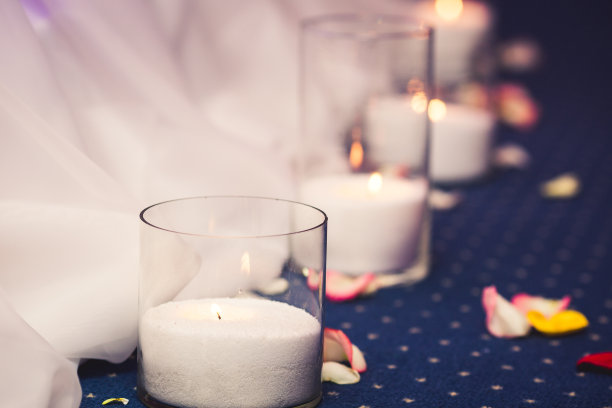 玻璃花瓶里插蜡烛，花瓣环绕。婚礼装饰。图片下载