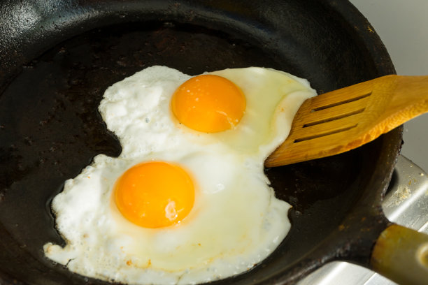 早餐吃两个鸡蛋。在煎锅里煎鸡蛋。图片下载