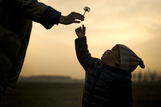 年轻的妈妈给宝宝蒲公英，侧视图片下载