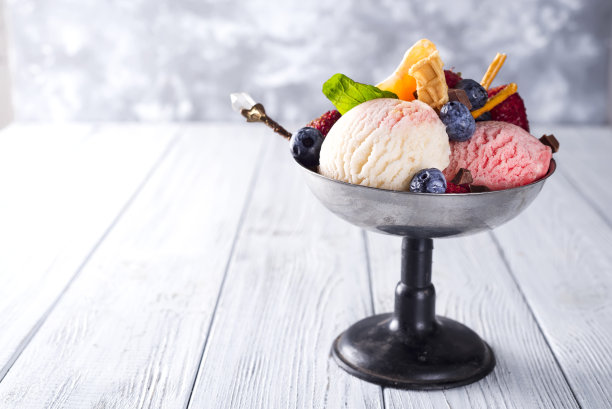 碗里有三种不同颜色的冰淇淋，白色，黄色，红色，华夫蛋筒，巧克力，橘子和吸管图片下载