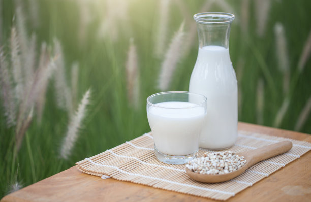 以大自然为背景往玻璃杯里倒牛奶。图片下载