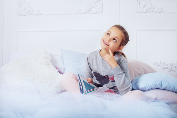 小女孩在床上看书。童年的概念和e图片下载
