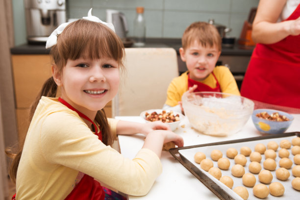妈妈和她的孩子做饭准备面团，在家里的厨房烤饼干。休闲生活照片系列在现实生活的室内图片下载