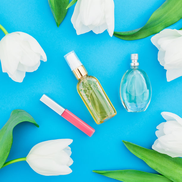 女性香水，奶油，口红和白色郁金香花在蓝色的背景。美丽的博客。平躺，俯视图图片下载