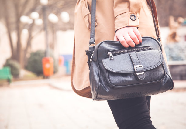 公园里拿着黑色皮包的女人。图片下载