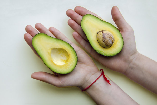 孩子们的手掌上有两半块新鲜鳄梨图片下载