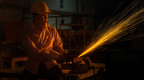 工人使用研磨切割机切割金属，在微光下聚焦于尖锐火花的闪光线图片下载