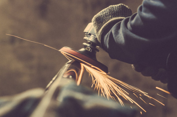 用带抛光盘的手工砂光机进行金属抛光。健美的形象。图片下载