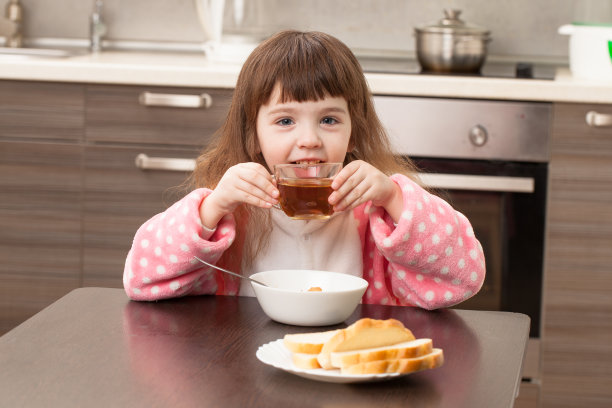 在厨房里吃饭的女孩。的童年。图片下载