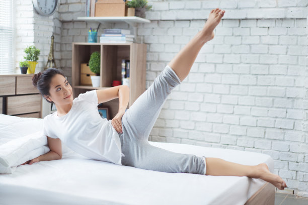 亚洲女性早上在床上锻炼，她觉得精神焕发。她表现得很谦卑。图片下载
