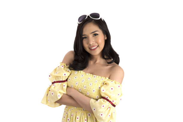 亚洲女孩穿着黄色花裙子，头戴太阳镜，双臂交叉站着。图片下载