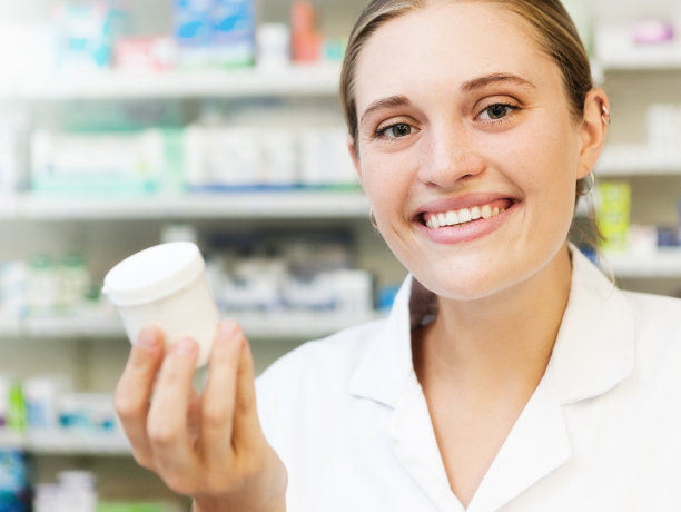漂亮的金发药剂师微笑着，拿着药片容器图片下载