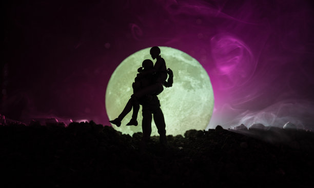 满月下接吻的情侣剪影。男孩亲吻女孩的手在满月剪影的背景。情人节装饰概念。一对情侣在月光下接吻的剪影图片下载