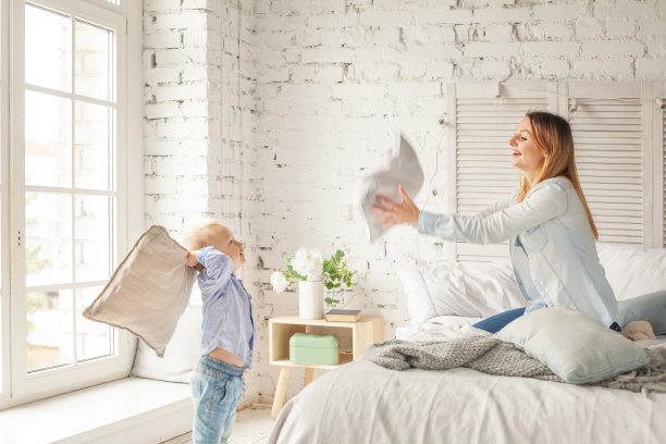 快乐的母亲和儿子在家里玩。枕头大战，幸福家庭图片下载