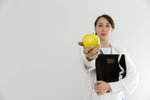 营养学家医生拿着天平和苹果。节食、健康生活方式和营养理念图片下载