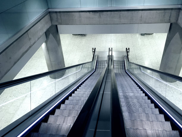 看着扶梯上没有人。在地铁站里可以下到另一层的自动扶梯。一个交通枢纽的干净和时尚的现代室内设计。添加单色照片滤镜。图片下载