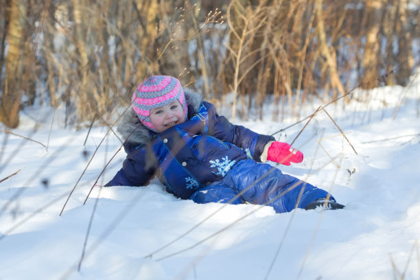 在阳光明媚的冬季公园里，小女孩用四肢在雪地上爬行图片下载