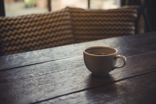 特写图像热咖啡杯上的古董木桌在咖啡馆图片下载
