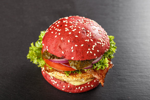 颜色红色汉堡。自制的美国鸡肉汉堡配甜菜根面包和蔬菜的汉堡。流行的食物。图片下载