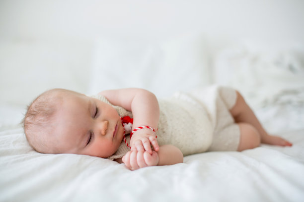 可爱的小男孩，玩着白色和红色的手镯图片下载