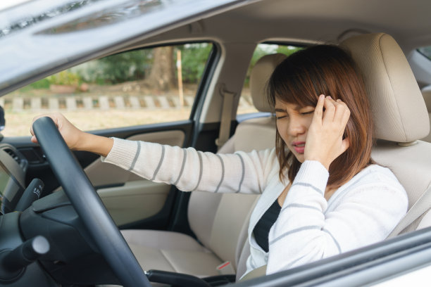 特写的年轻女子触摸她的太阳穴感到头痛在她的车后，开车了很长时间图片下载