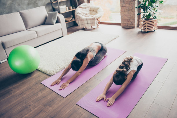 健康的思想寓于健康的身体之中!娇小可爱活泼好动的女儿和苗条运动精力充沛的妈妈正在室内地板上做伸展运动素材图片