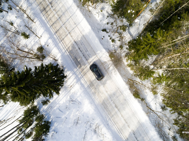 一辆汽车在冬季道路上的鸟瞰图。冬天的乡村景观。航拍雪域森林与一辆汽车在道路上。无人机从上面拍下的。航拍照片。四轴飞行器。图片下载