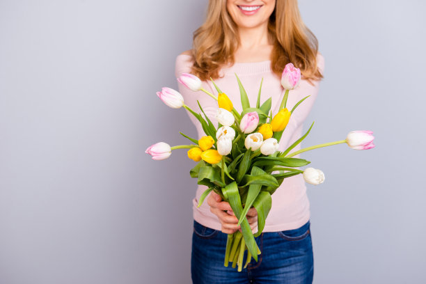 花开花开清新国际母性。美丽迷人的美丽美丽的绿色，白色，黄色，粉红色的郁金香在女人的手孤立的灰色背景复制空间的特写照片图片下载