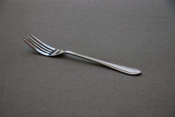 在餐厅用餐时，在灰色织物餐桌上使用清洁的小钢叉图片下载