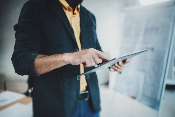 建筑师穿着正式的照片与数字平板电脑和图纸计划在现代照明办公室。水平。模糊的背景。图片下载